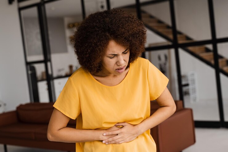 Mulher com verminose sente dores abdominais e põe mão sobre a barriga.