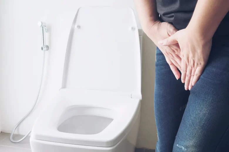 Imagem de uma pessoa com dor, representando sintomas comuns de infecção urinária, ao lado de um vaso sanitário.