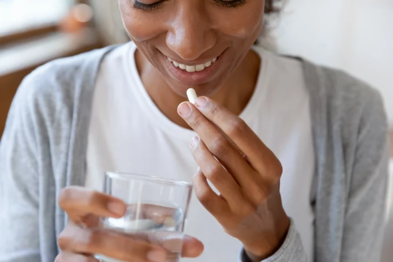 Mulher pronta para tomar Nimesulida com um copo de água, destacando o uso do medicamento para alívio da dor.