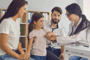 Família sorrindo em consulta pediátrica na Clínica SiM, mostrando os benefícios do Cartão SiM para o cuidado da saúde de pais e filhos.