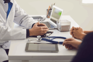 Médico em consultório explicando para o paciente sobre o procedimento de endoscopia digestiva, seus preparos e importância para o diagnóstico.